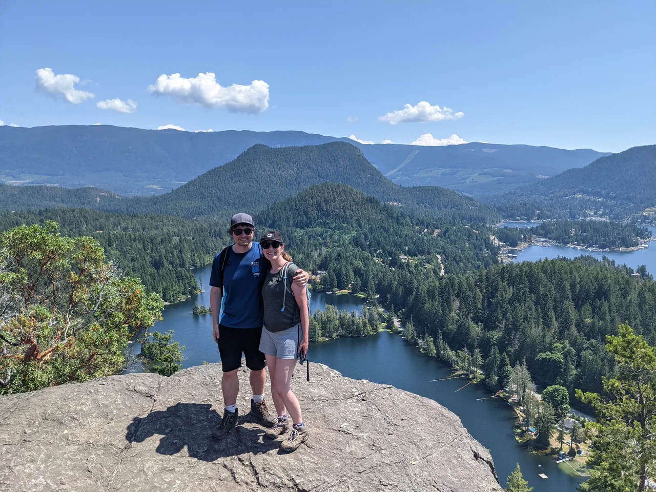 Hannah and Mike on a rocky viewpoint overlooking forested lakes