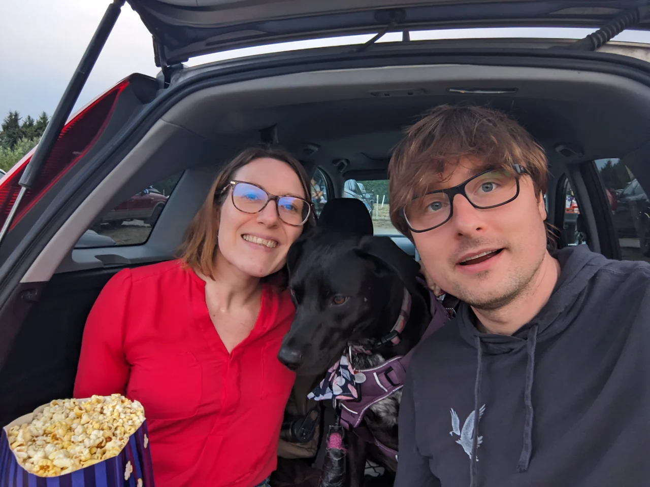 Hannah and Mike with Luna and popcorn at the open boot of a car