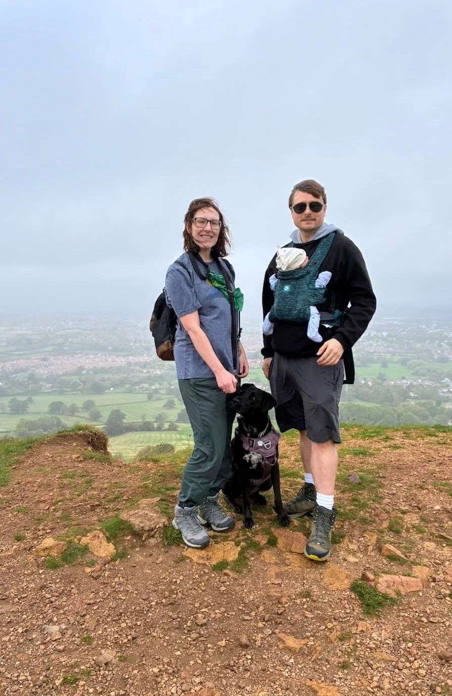Hannah and Mike on a hilltop with Nolan in a carrier and Luna beside them