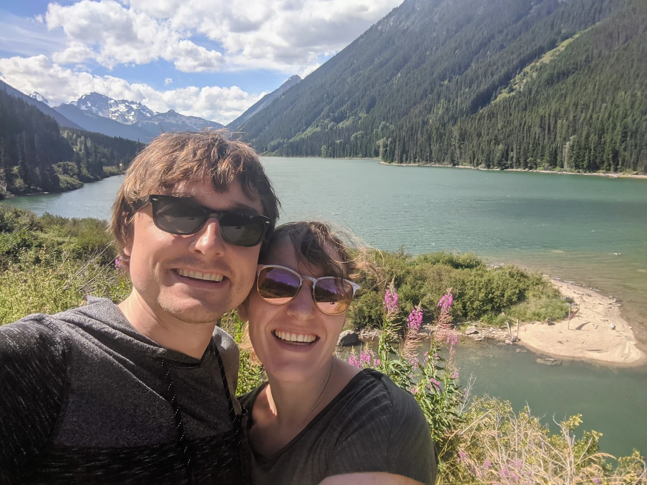 Hannah and Mike smiling together beside a mountain lake